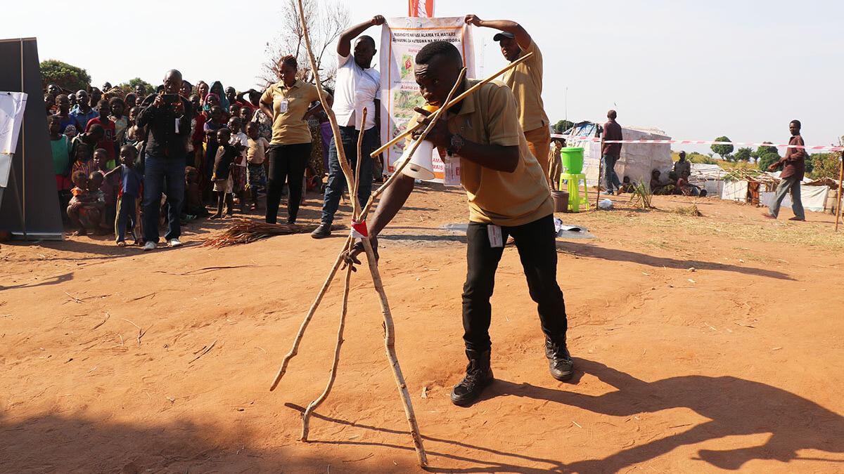 A Community Liaison Officer is illustrating the marking of a suspected explosive item with tree branches