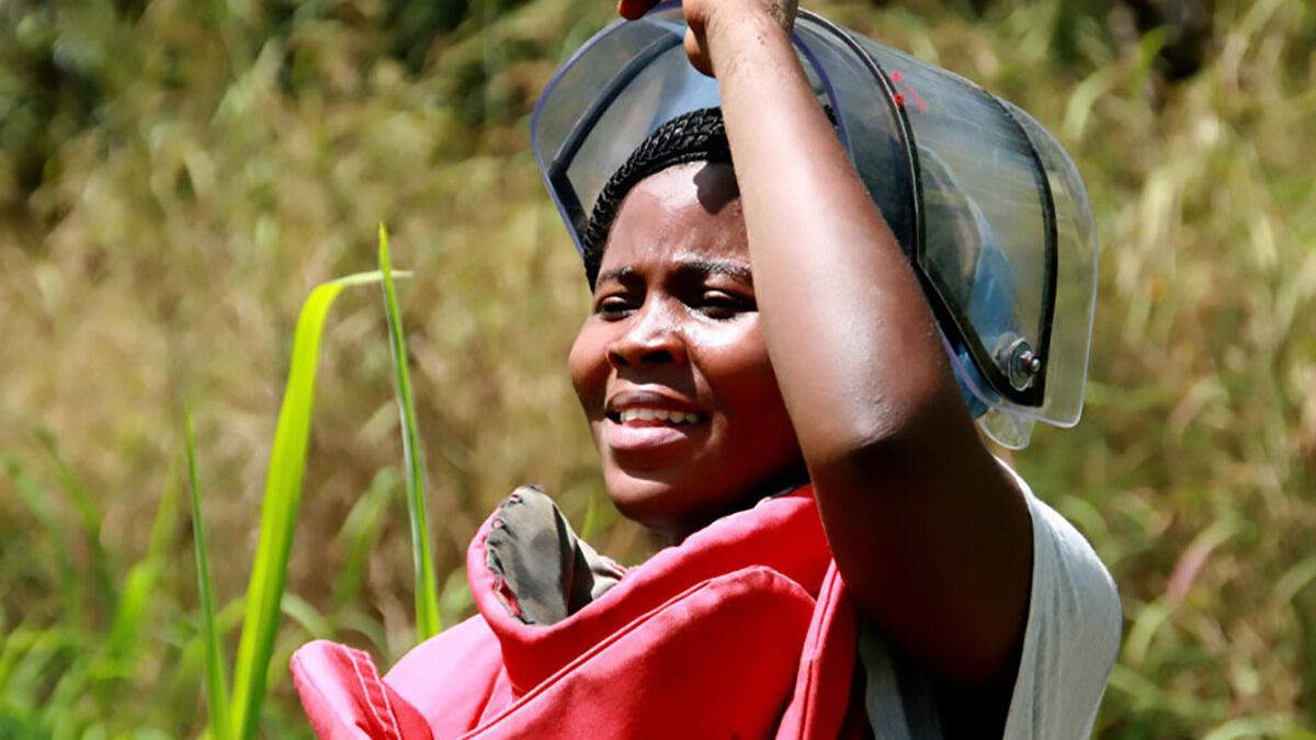 a female deminer is uncovering her mask