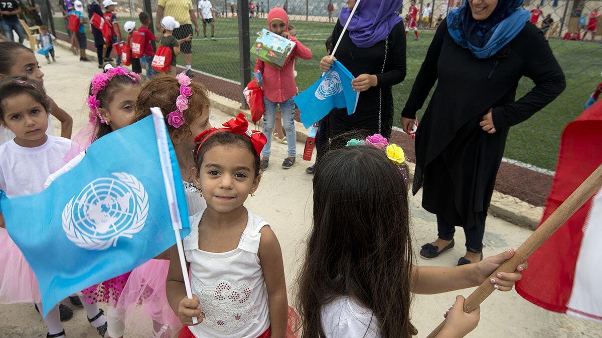 a girl is smiling and holding an UN flag