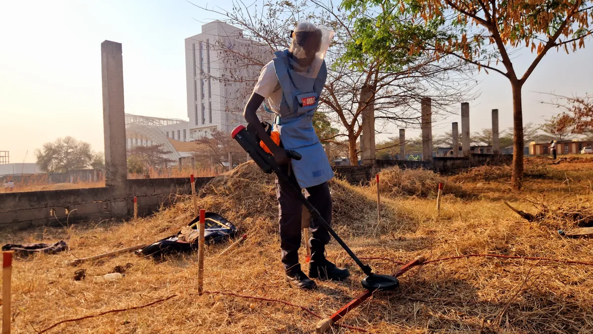 a deminer is deminig the field with a detector