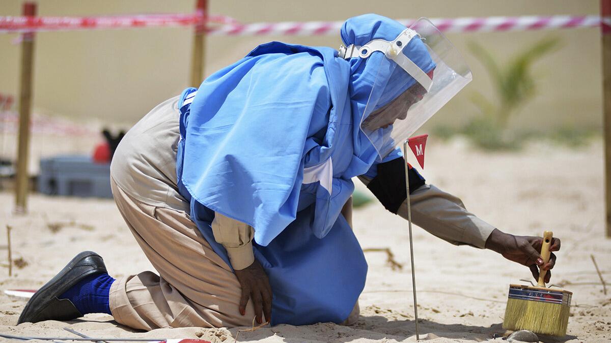 A female member of an Explosive Ordnance Disposal team brushes sand off of a mortar shell during a demonstration held by UNMAS in Mogadishu, Somalia.