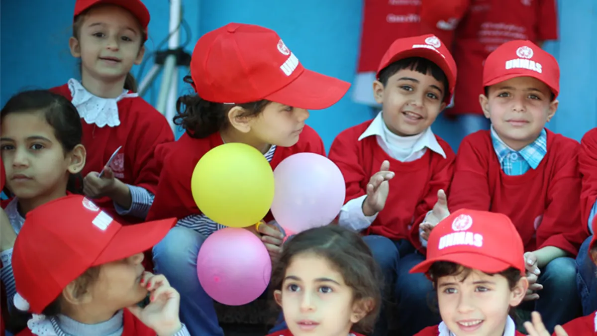 Children wearing UNMAS hat with red t-shirt