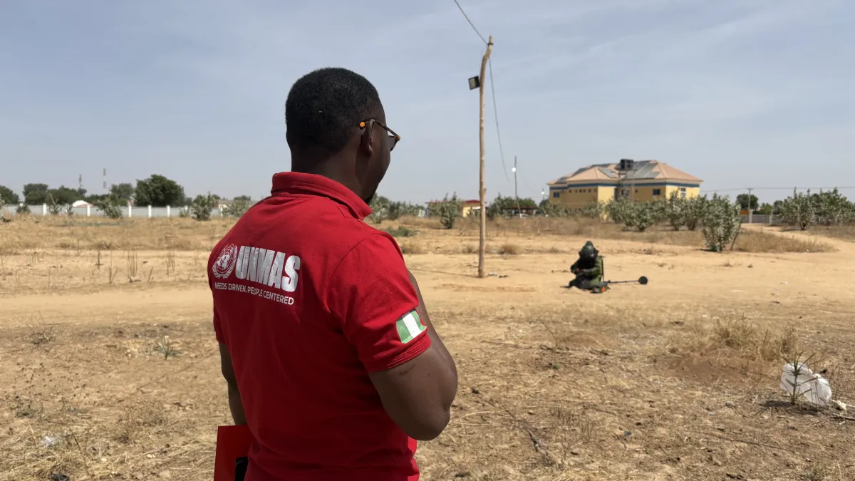 a man with UNMAS shirt overlooking a deminer