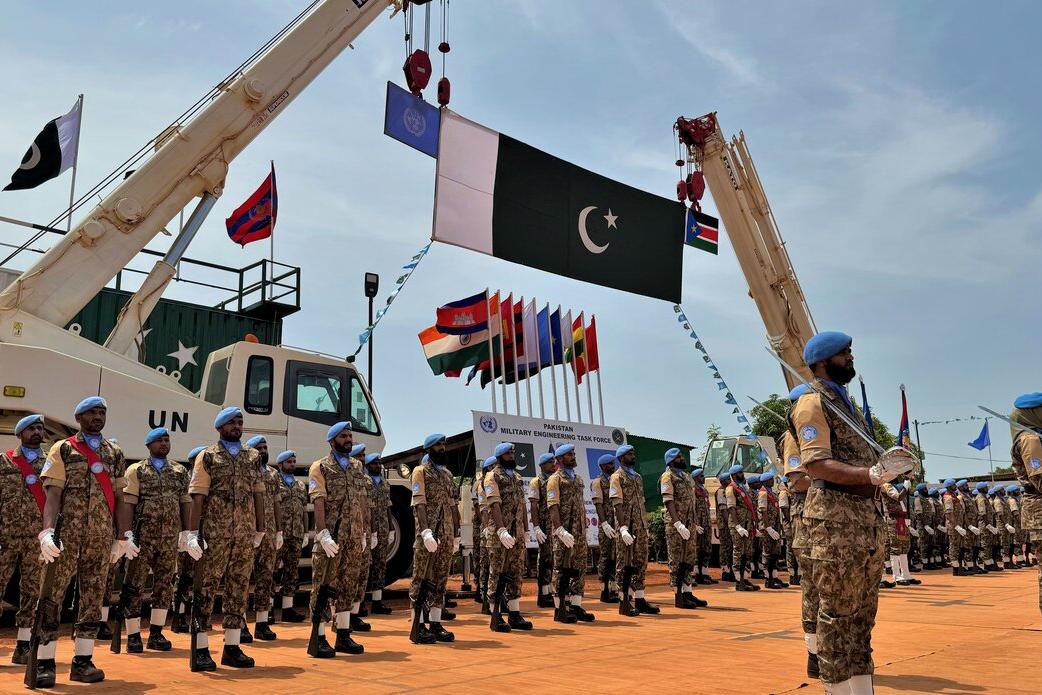 Pakistani peacekeepers standing in formation under the Pakistani flag.
