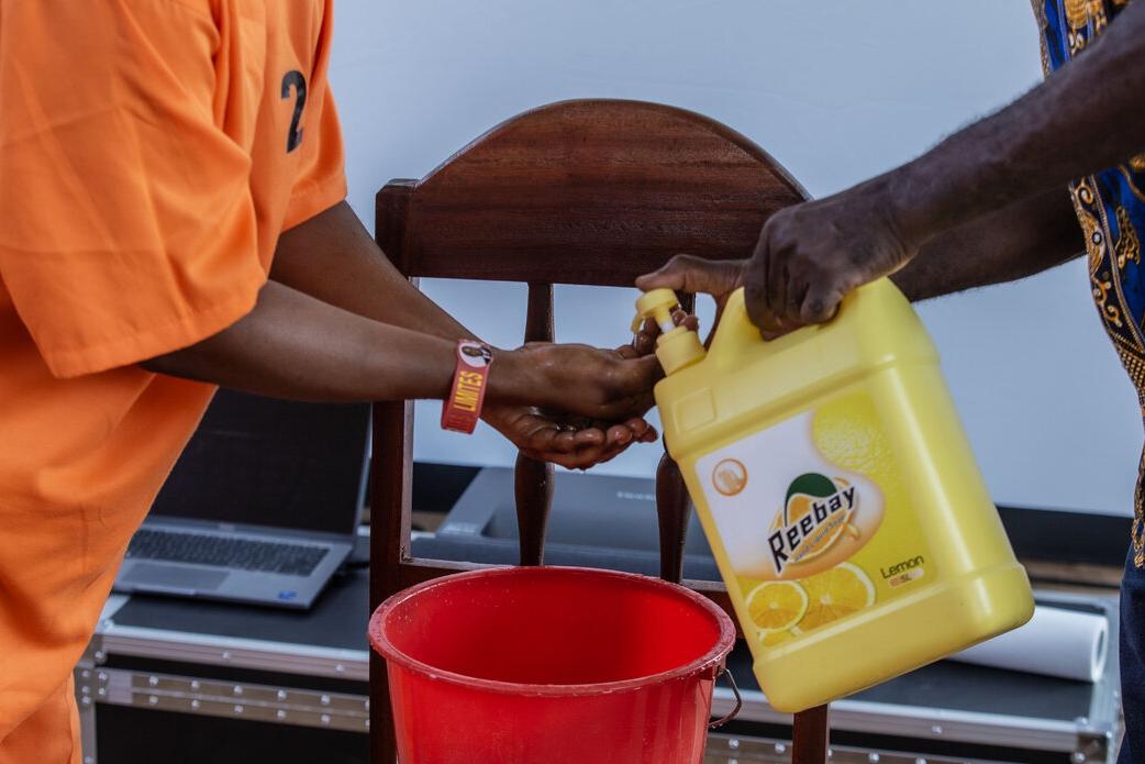 Une personne en combinaison orange se lave les mains