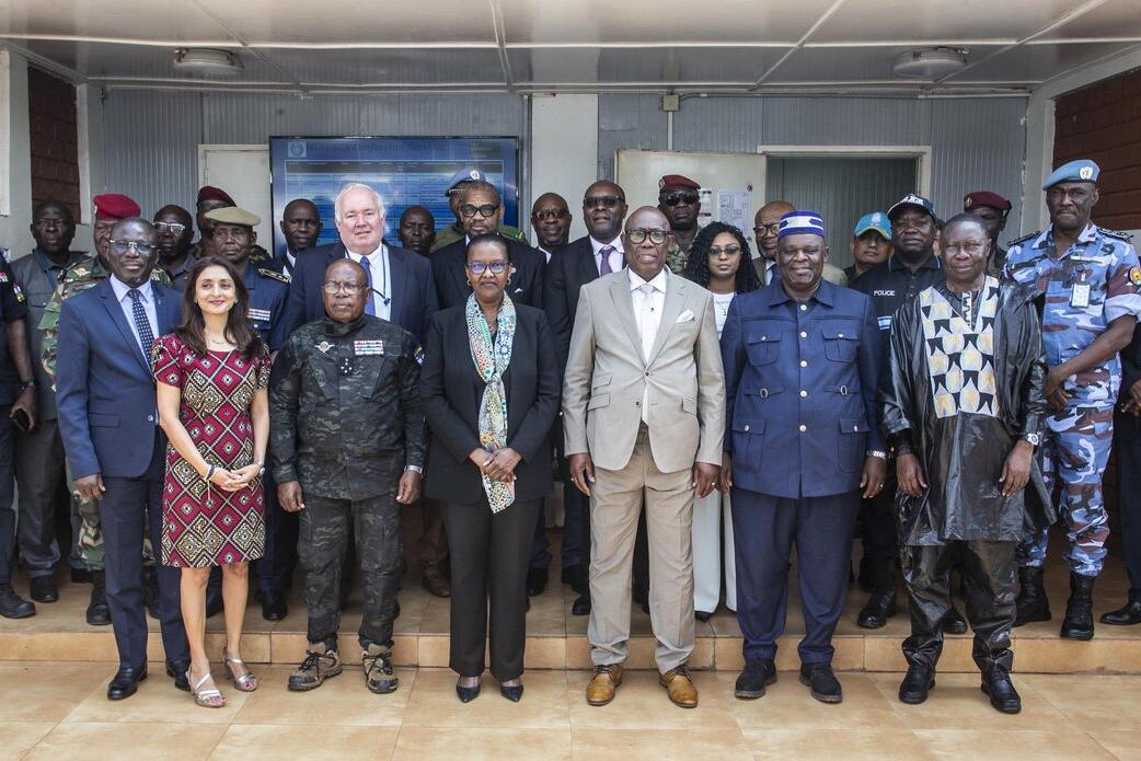 Un groupe de personnes en tenue militaire et civile se tient en rangs pour une photo