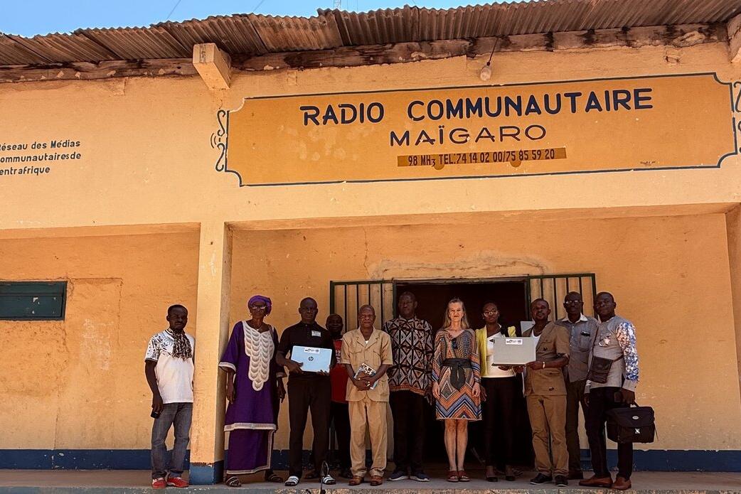 Des personnes se tiennent devant un bâtiment avec une pancarte qui indique Radio Communautaire Maigaro