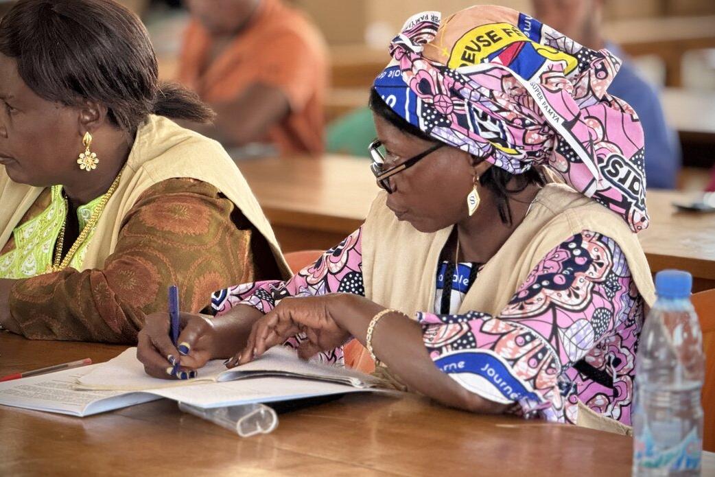 Un participant à une réunion écrit dans un carnet.