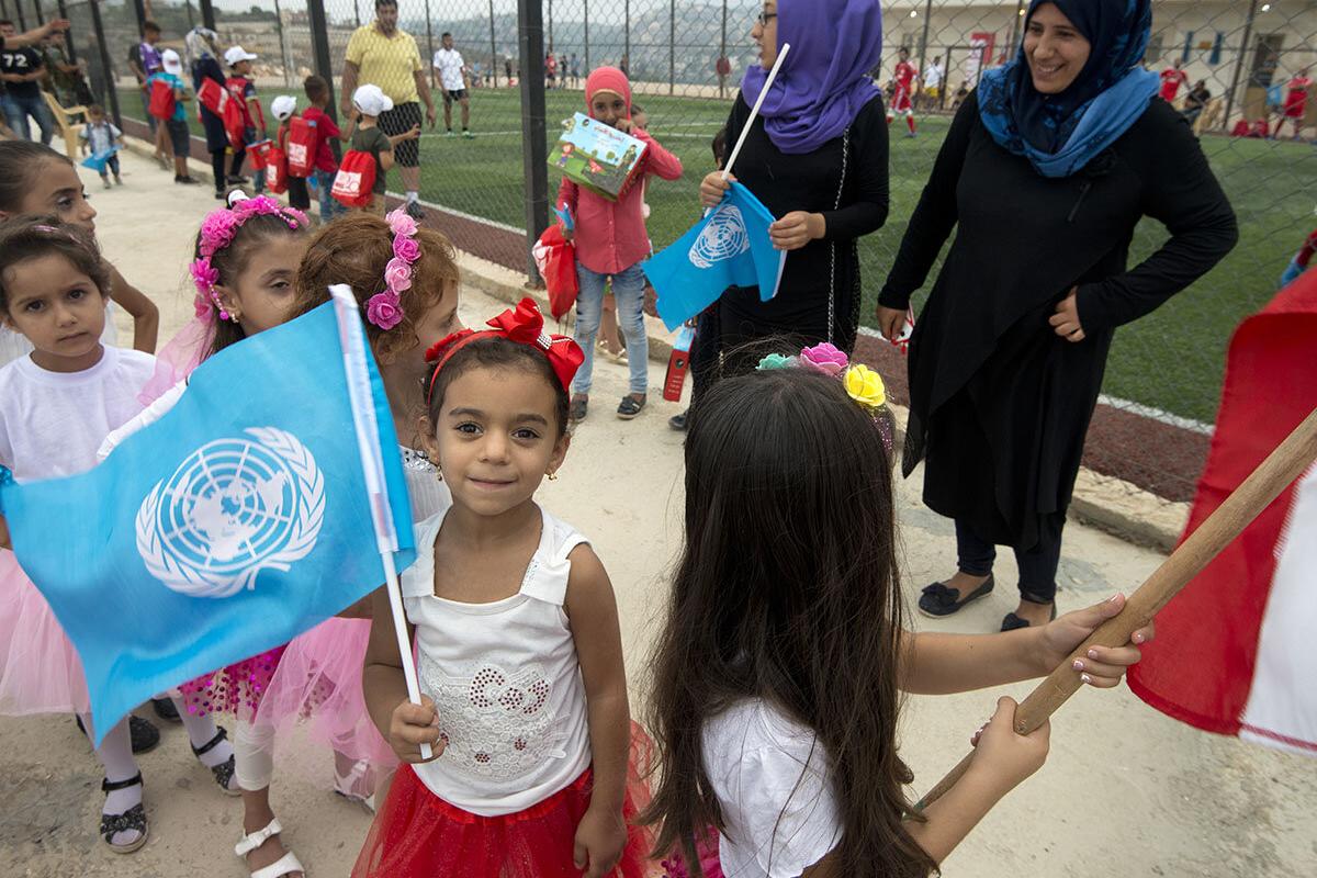 a girl is smiling and holding an UN flag