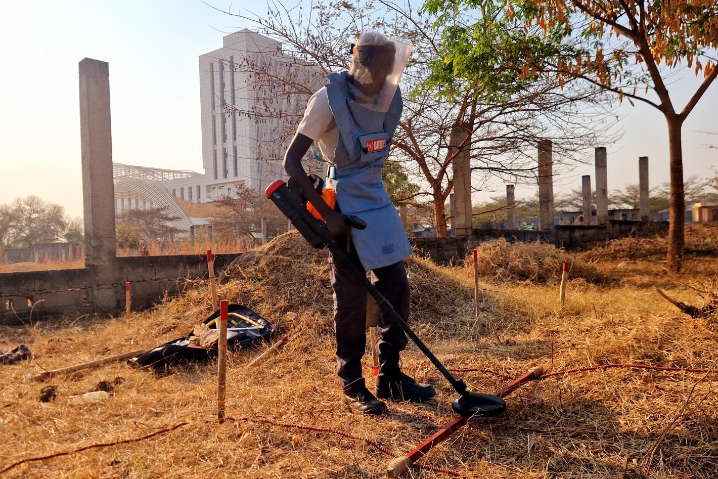 a deminer is deminig the field with a detector