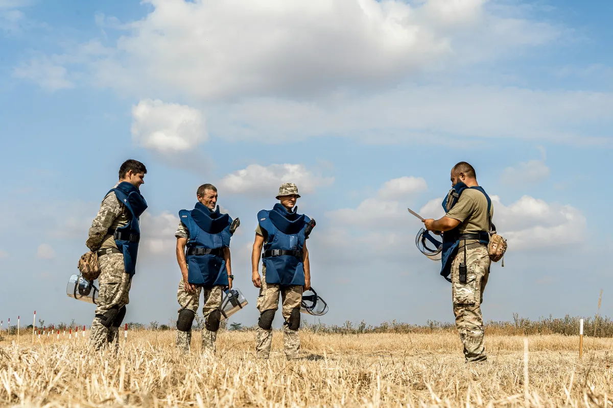 A group of SSTS deminers undergo a briefing before starting work on a potentially contaminated field in the Mykolaiv region.