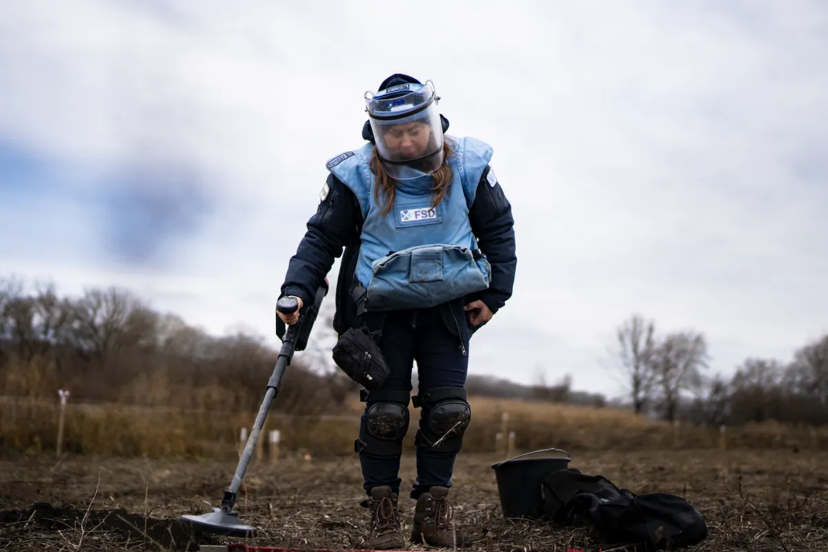 a female deminer is working in a field