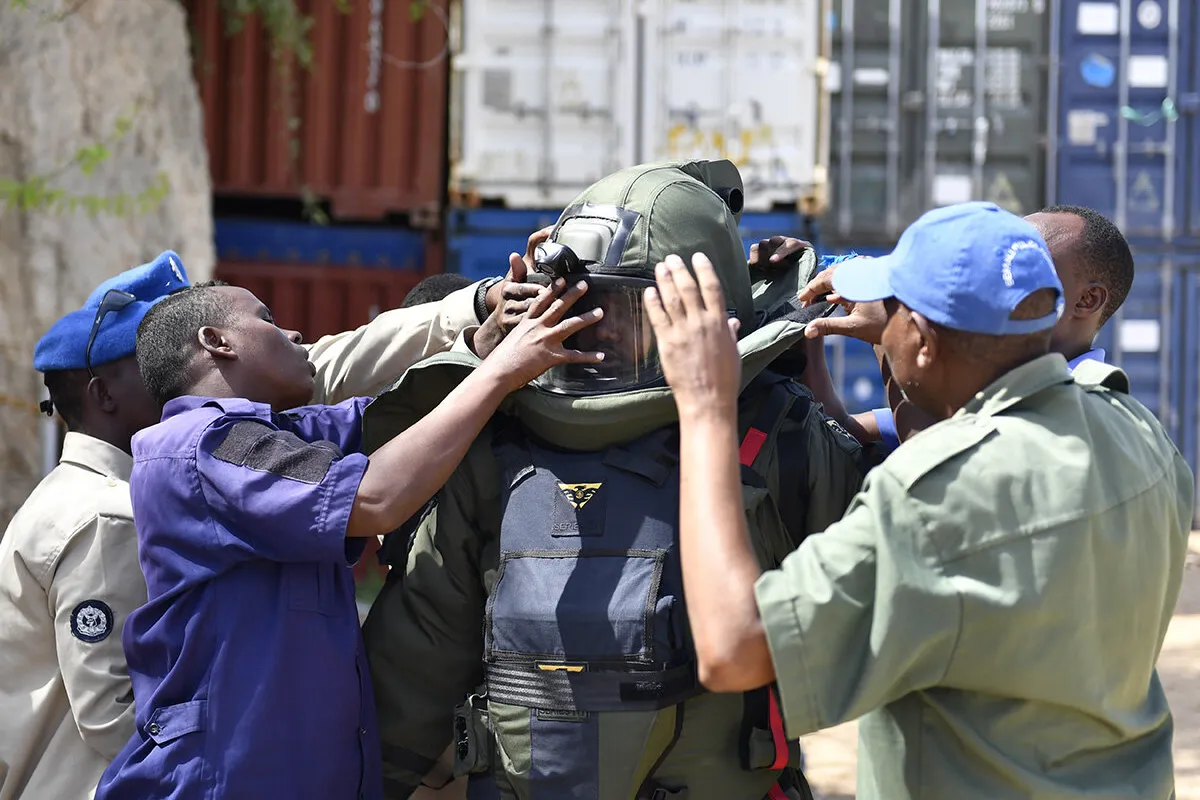 some men are helping a police to wear a protective mask