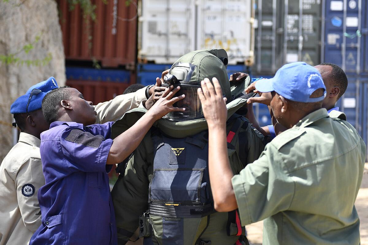 some men are helping a police to wear a protective mask