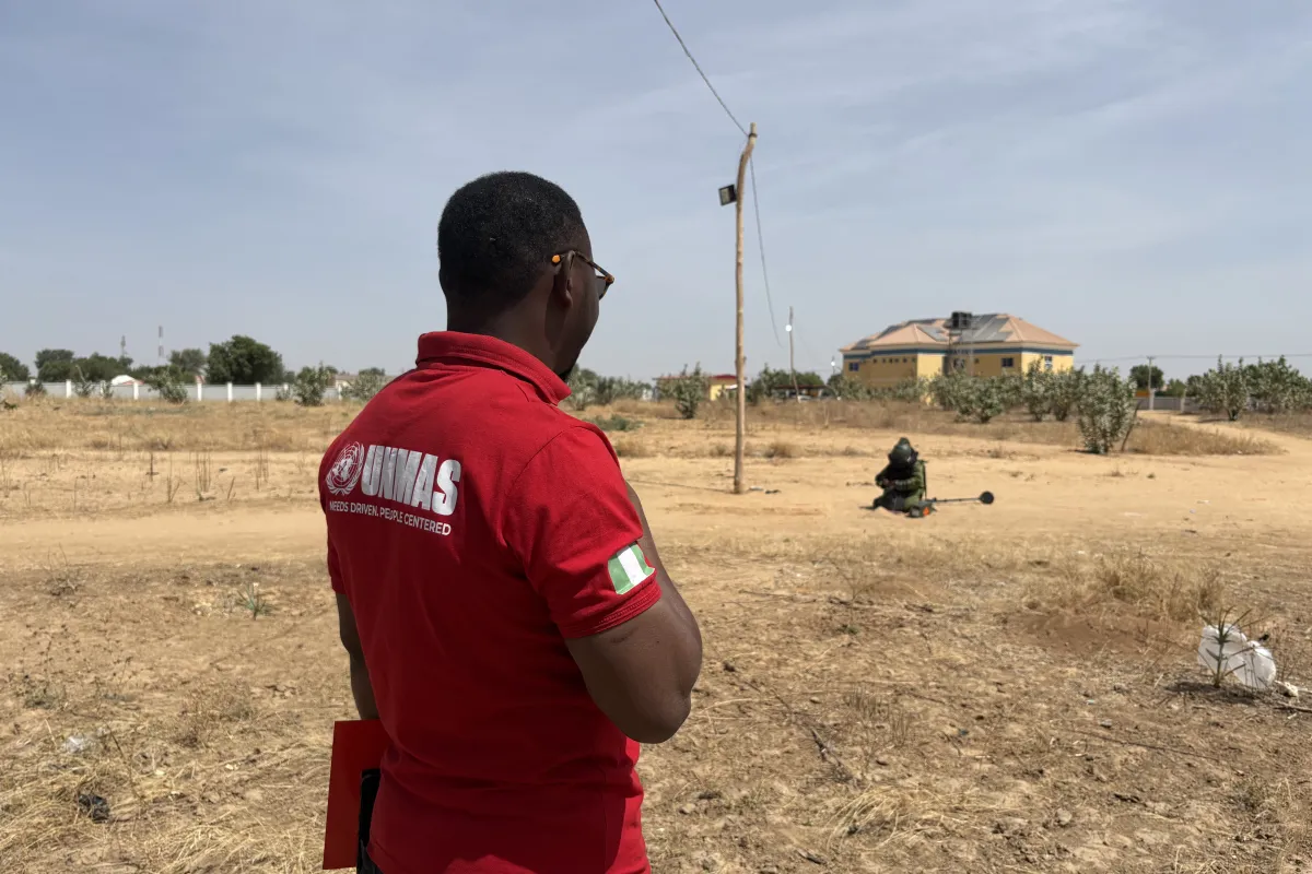 a man with UNMAS shirt overlooking a deminer