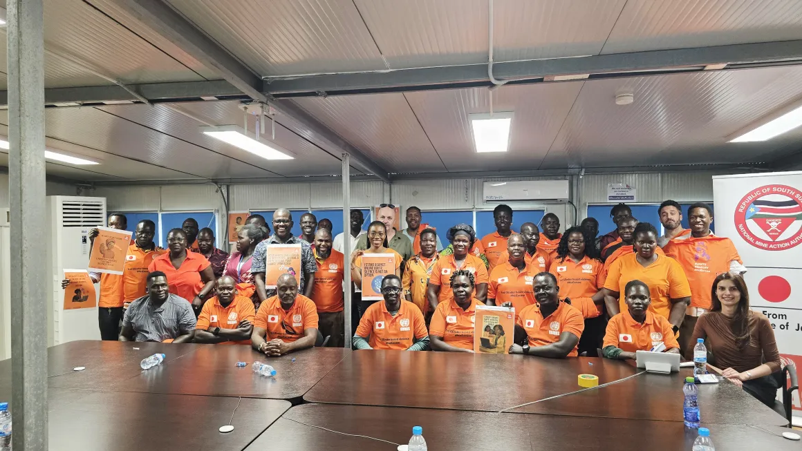 a group of people in orange shirt with a banner behind them.