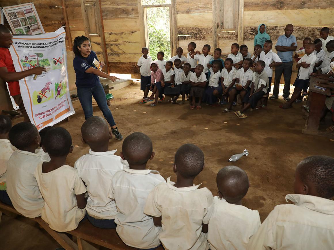 a woman is delivering mine risk education to a group of children