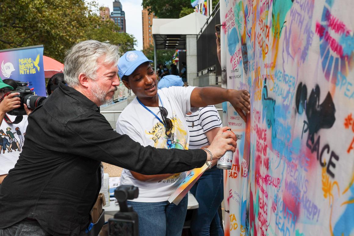 a woman is helping a man doing graffiti