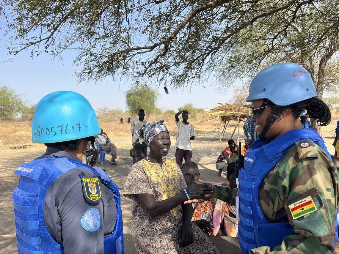 Two women police and military peacekeepers with a community member.