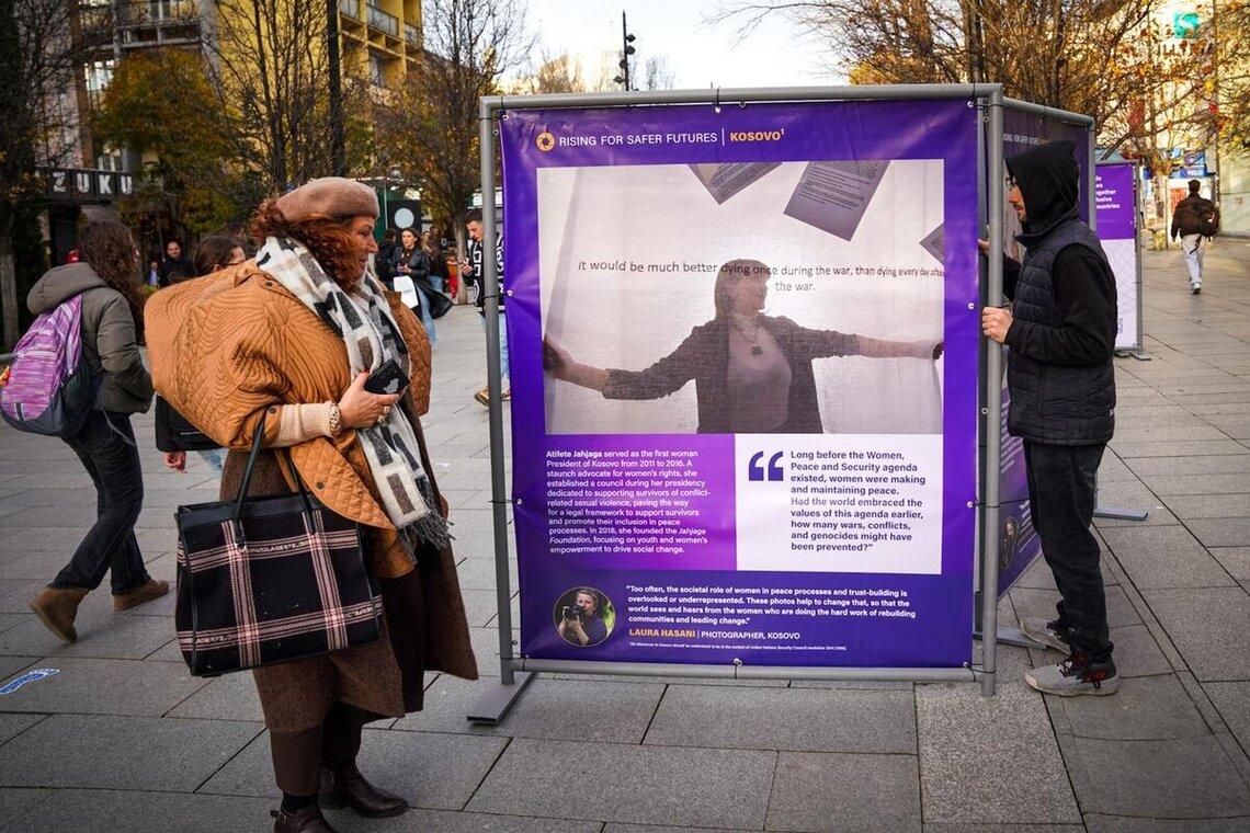 People walking in front of event banner.