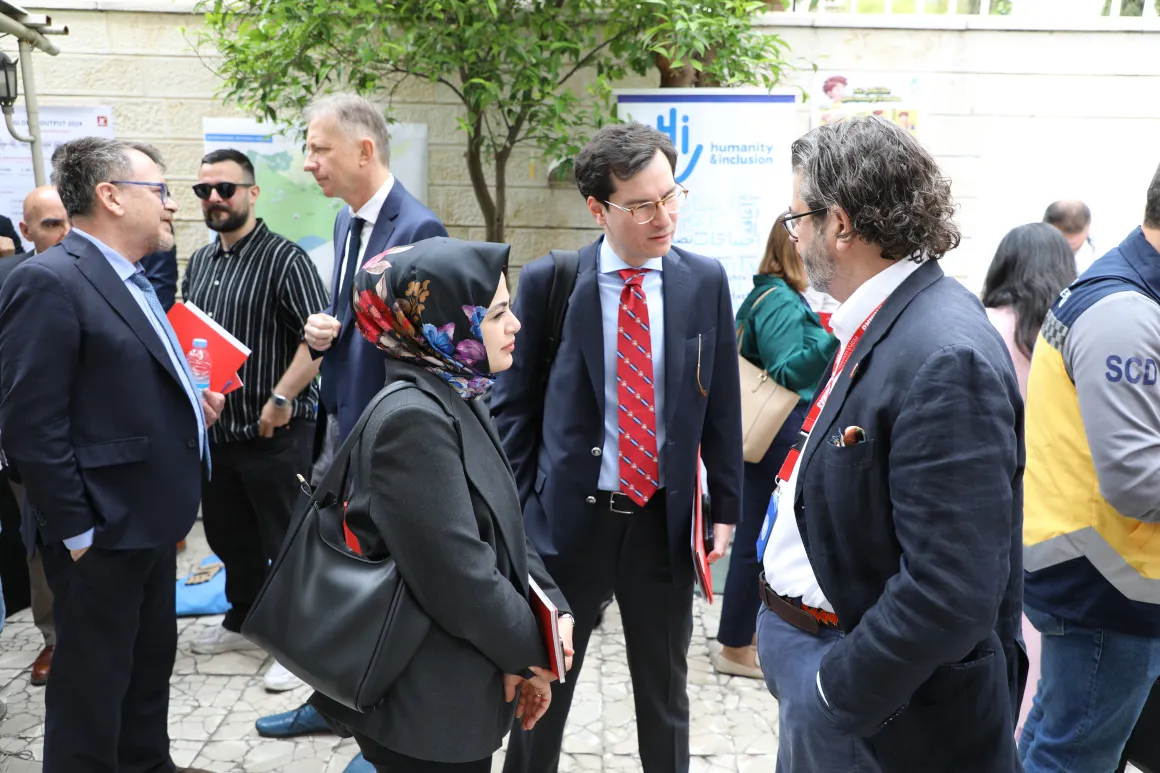 Three people wearing suits are chatting with each other.