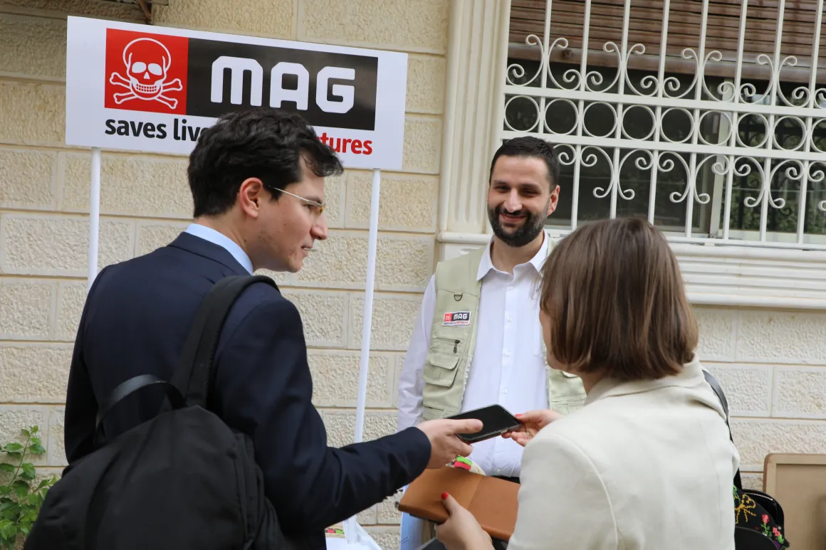 Three people are chatting with each other in front of a sign.