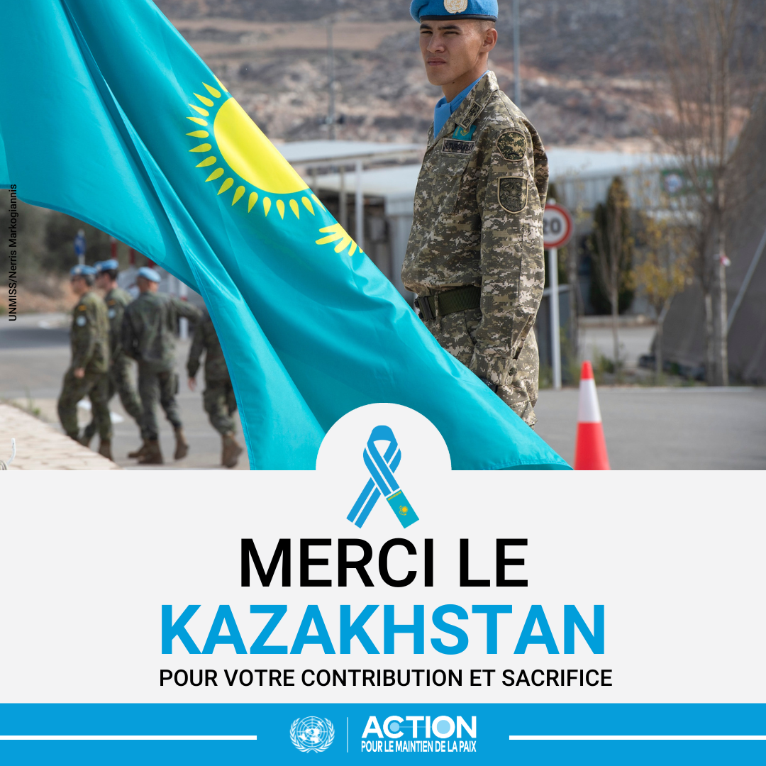 Un homme portant l'uniforme des Casques bleus debout à côté d'un drapeau