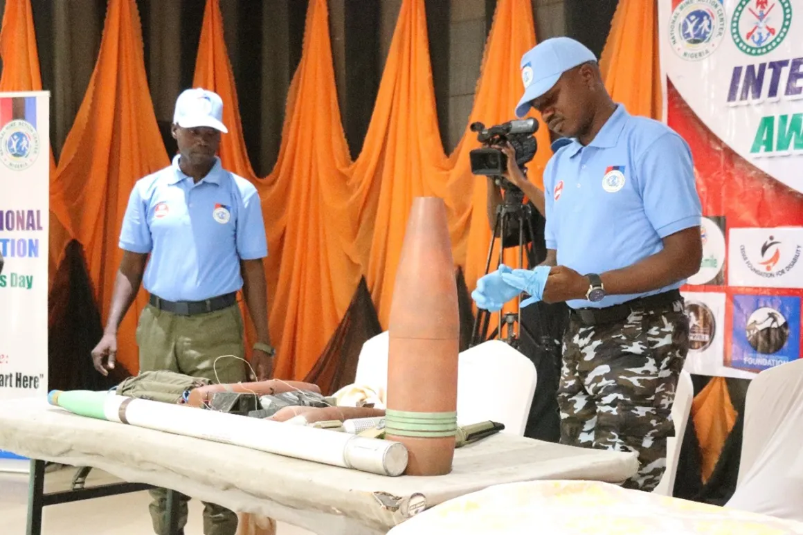 Two men standing around a table of exhibit explosive ordnances